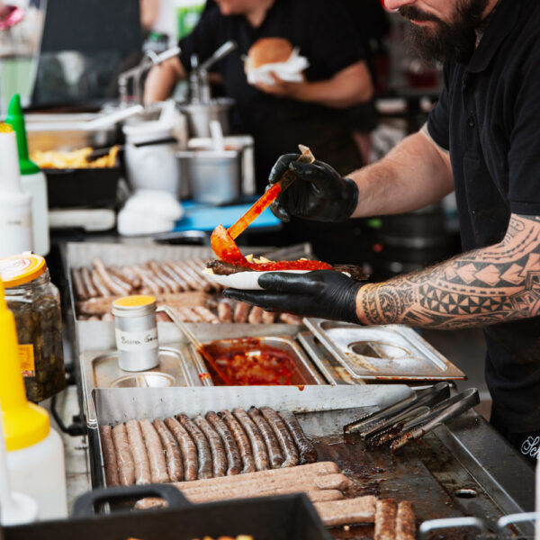 Mann bereitet vegane Bosna bei seinem Stand zu